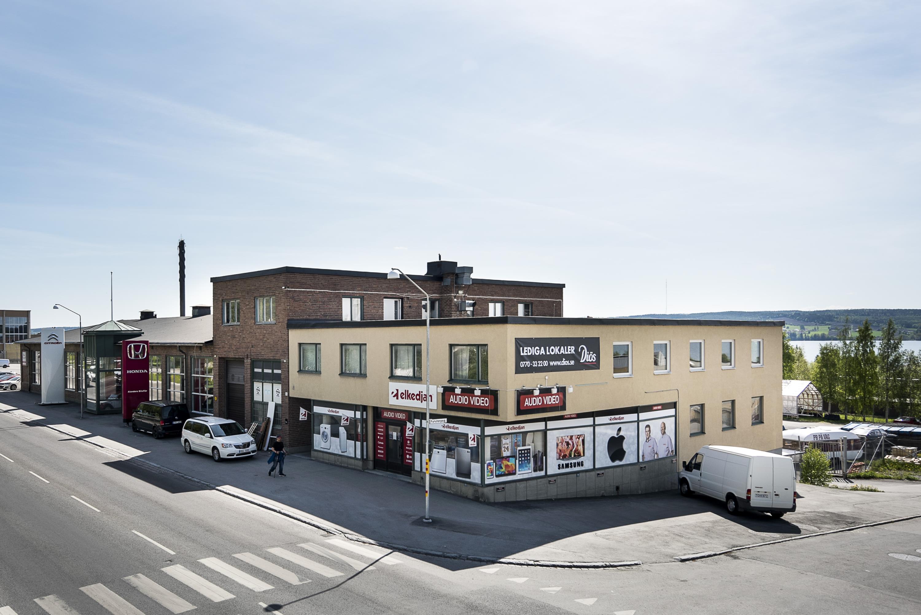 Beige byggnad sammanbyggd med byggnad i tegel. 