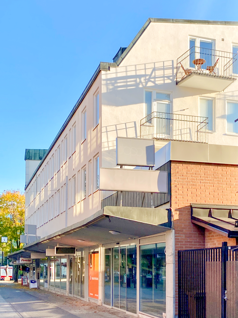 Vit byggnad i 4 våningar med balkonger på kortsidan.