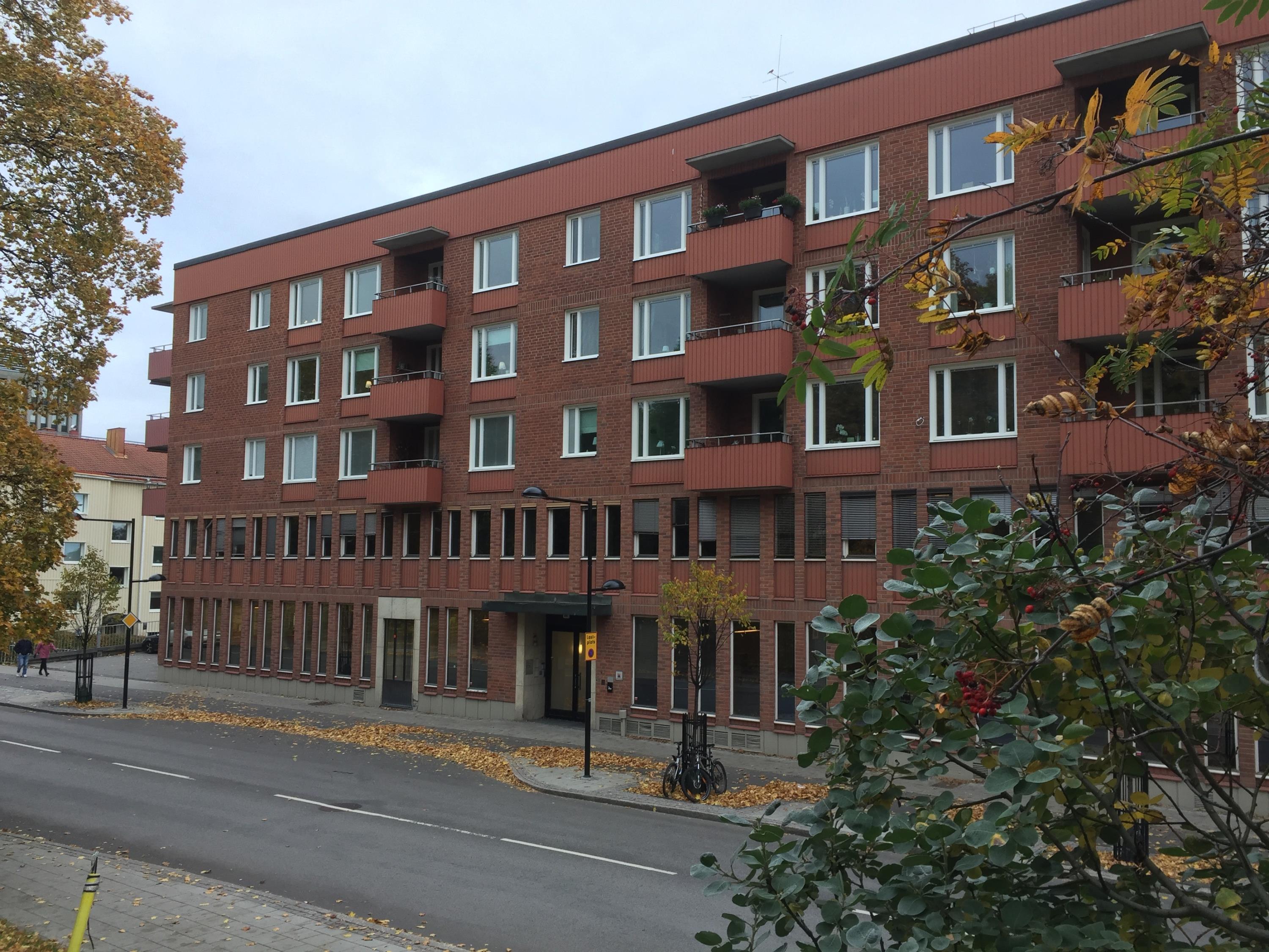 Tegelbyggnad 5 våningar med balkonger på de tre översta våningarna. 